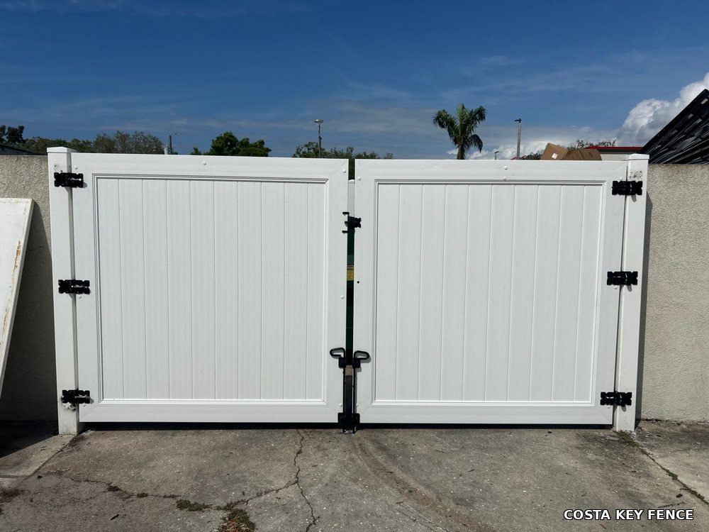 White vinyl commercial double gate installed by Costa Key Fence for a business parking lot near Sarasota, Florida