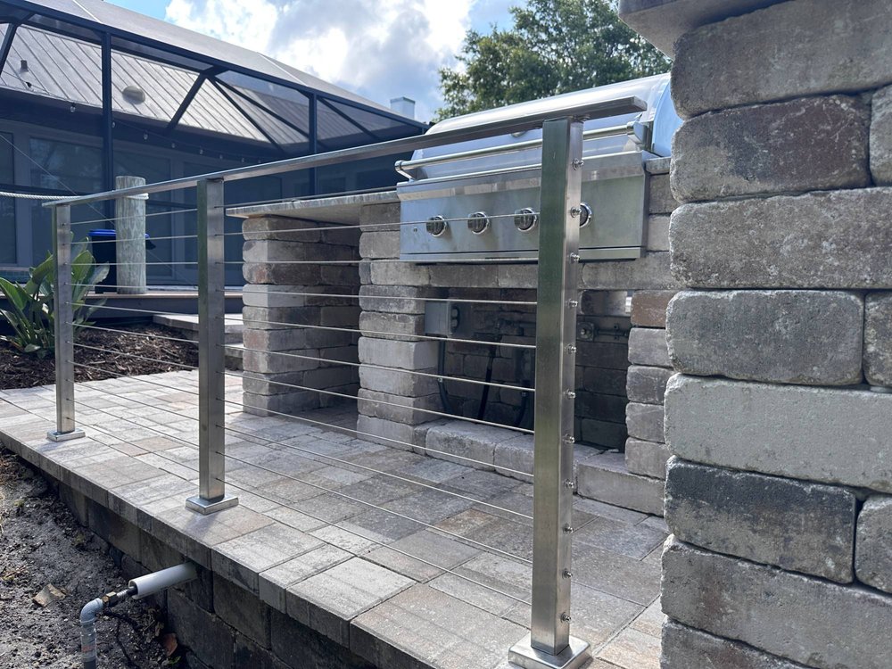 Stainless steel cable railing installed by Costa Key Fence along a paver patio and outdoor kitchen near Sarasota, Florida