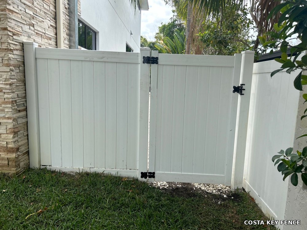 White vinyl privacy gate and matching fence by Costa Key Fence beside a stucco home near Sarasota, Florida